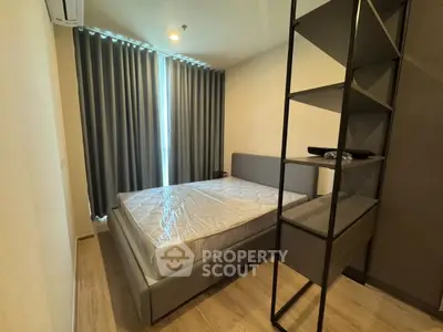 Modern bedroom with stylish bed and shelving, featuring elegant curtains and wooden flooring.