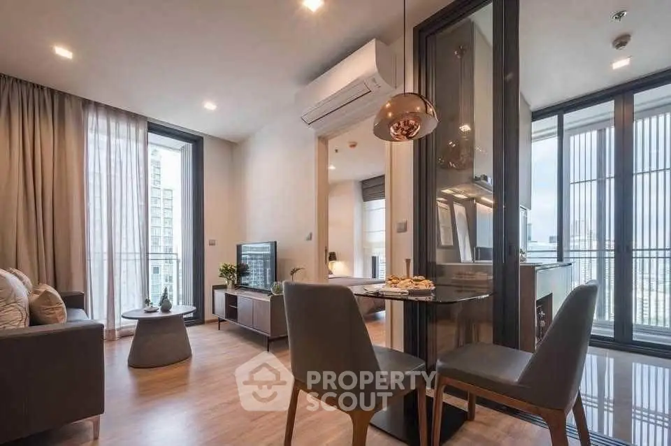 Modern living room with open kitchen and city view, featuring stylish decor and ample natural light.