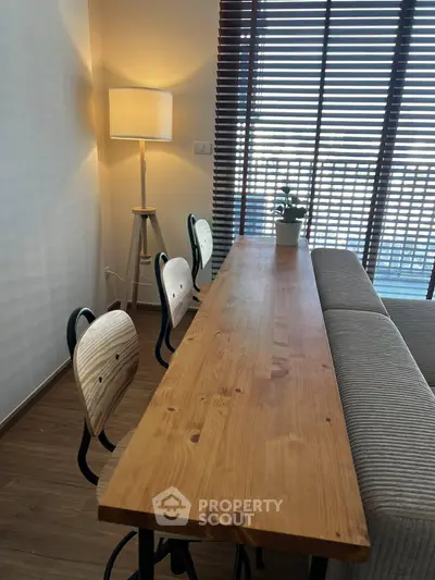 Modern dining area with wooden table and stylish chairs, featuring floor-to-ceiling windows with blinds.