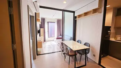 Modern apartment with open layout dining and living area, featuring sleek furniture and natural light.