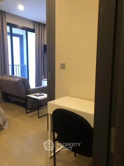 Modern apartment interior with cozy living room and study area, featuring sleek furniture and natural light.