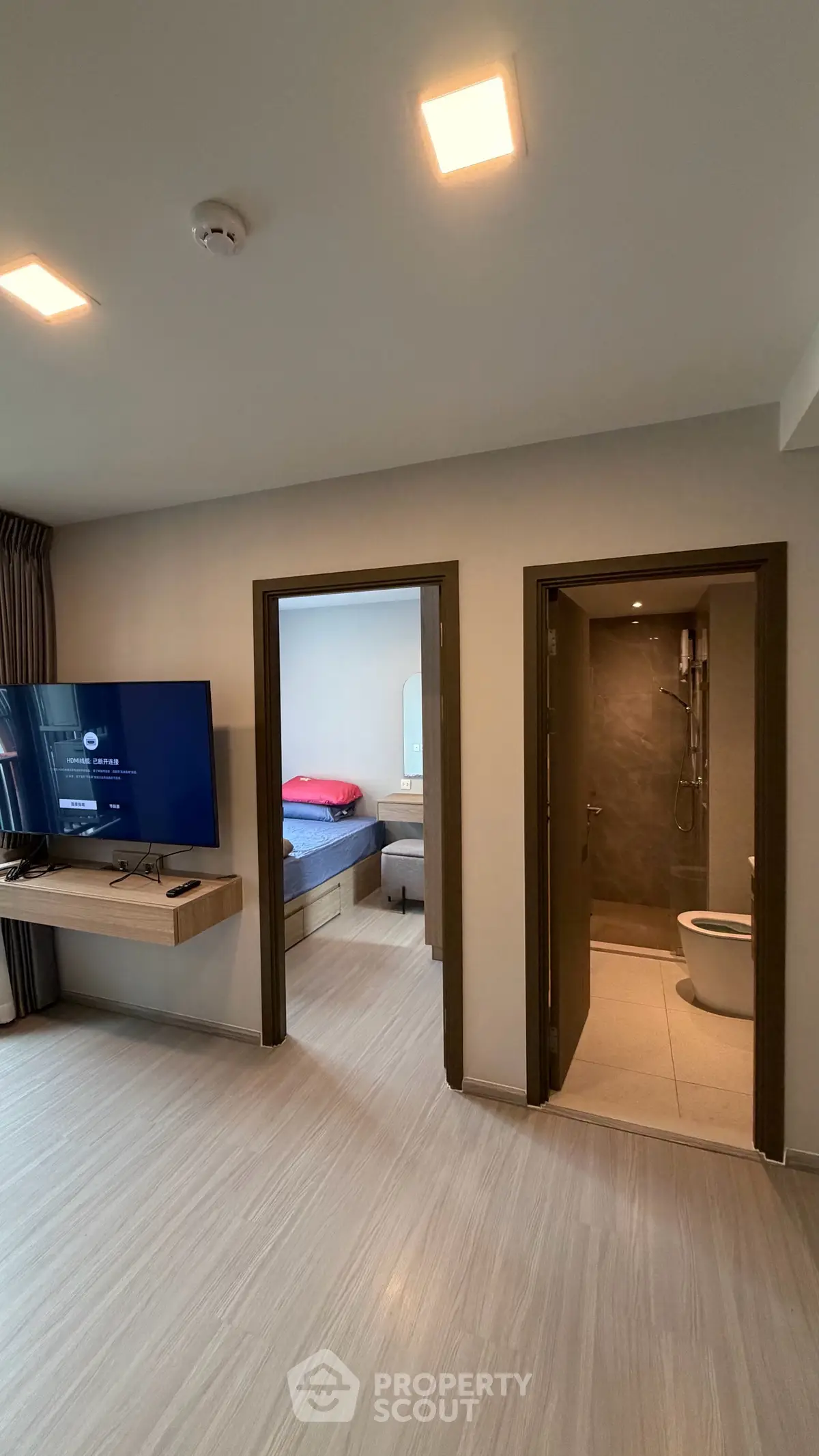 Modern apartment interior with living room, bedroom, and bathroom view, featuring sleek design and natural lighting.