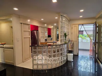 Elegant kitchen with glass block bar and modern appliances, opening to a bright balcony.