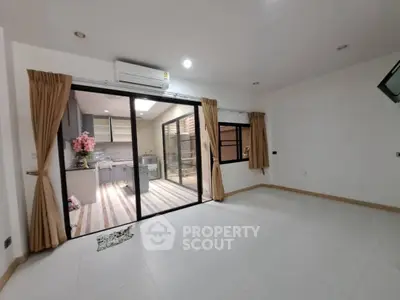 Spacious modern living room with open kitchen and large sliding glass doors.