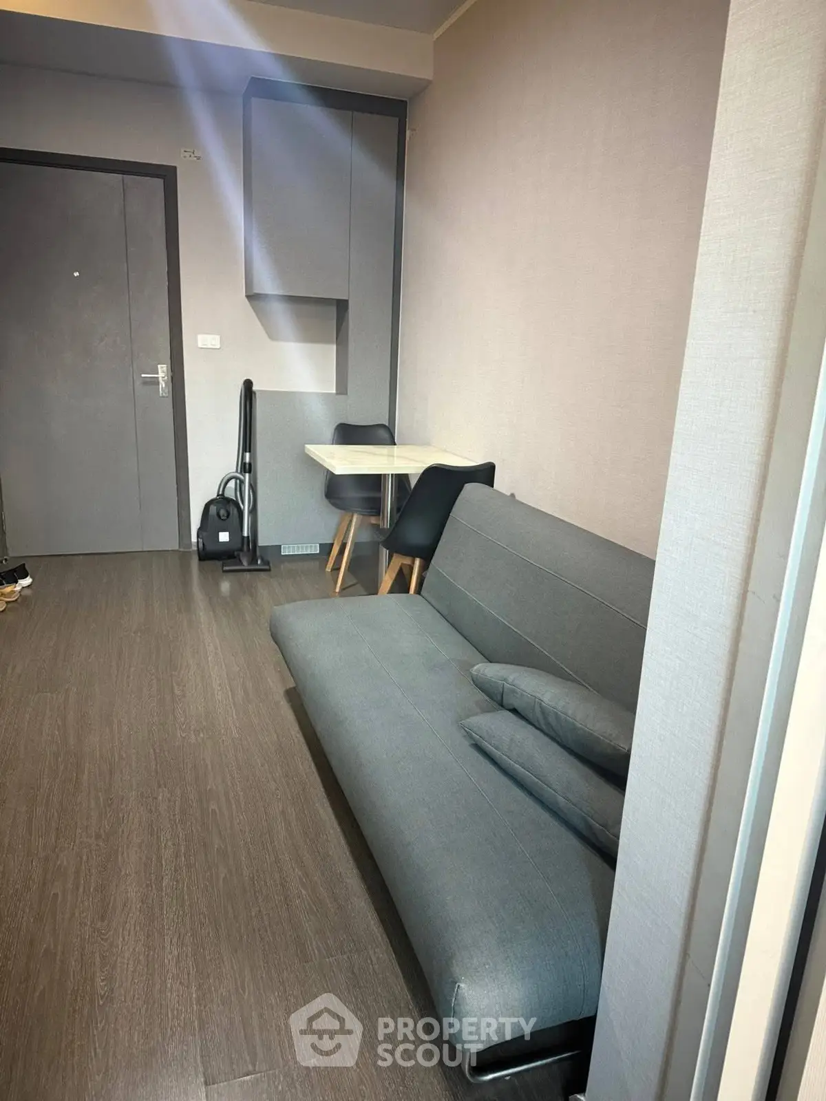 Modern living room with sleek gray sofa and compact dining area