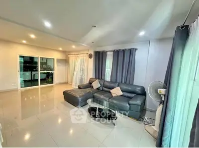 Spacious living room with modern leather sofa and glass coffee table, perfect for relaxation.
