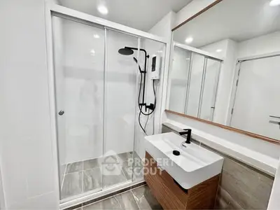 Modern bathroom with sleek shower and stylish vanity in contemporary apartment.