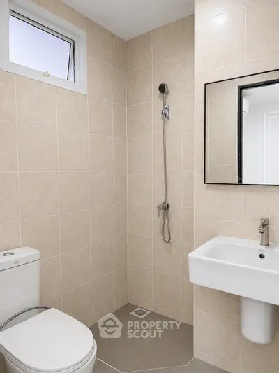 Modern bathroom with beige tiles, wall-mounted shower, and sleek fixtures.