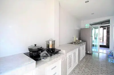 Modern kitchen with sleek countertops and gas stove, featuring open layout and ample natural light.