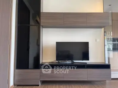 Modern living room with sleek wooden furniture and large TV setup.