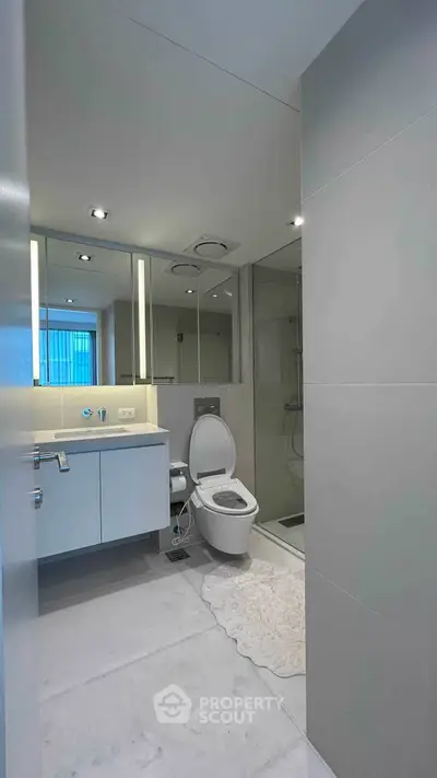 Modern bathroom with sleek fixtures and large mirror in a contemporary apartment.