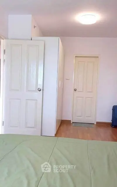 Spacious bedroom with wooden flooring and ample natural light