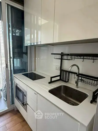 Modern compact kitchen with sleek white cabinetry and built-in appliances.