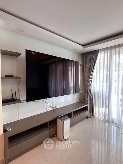 Modern living room with large TV and sleek furniture, featuring floor-to-ceiling windows and elegant curtains.