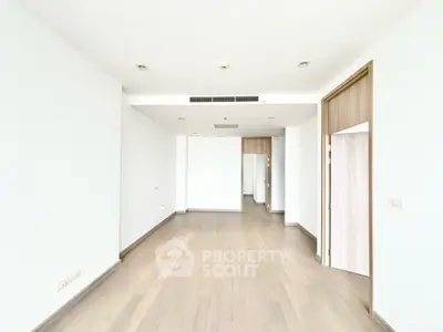 Spacious empty living room with wooden flooring and modern design, ready for customization.