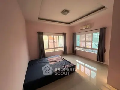 Spacious bedroom with large windows and natural light, featuring a minimalist design and air conditioning.