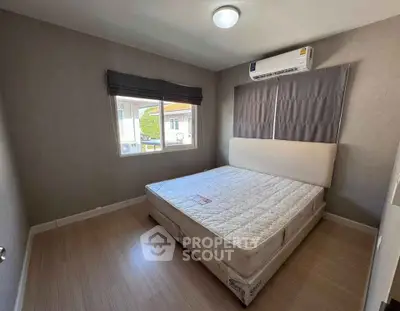 Cozy bedroom with natural light and modern air conditioning unit, perfect for restful nights.