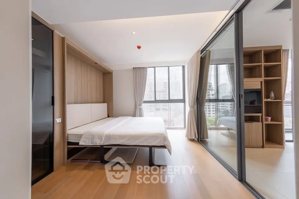 Modern bedroom with large windows and wooden flooring in a stylish apartment.