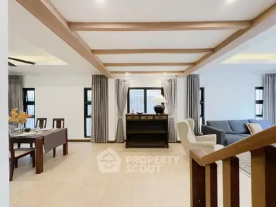 Spacious living room with modern decor and natural light, featuring wooden beams and elegant furnishings.