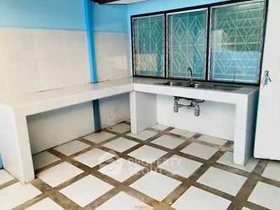 Spacious kitchen with tiled countertops and geometric window design