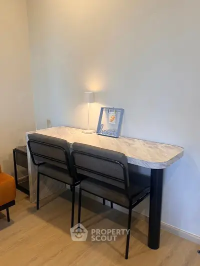 Modern study area with sleek marble desk and stylish chairs in a cozy apartment.