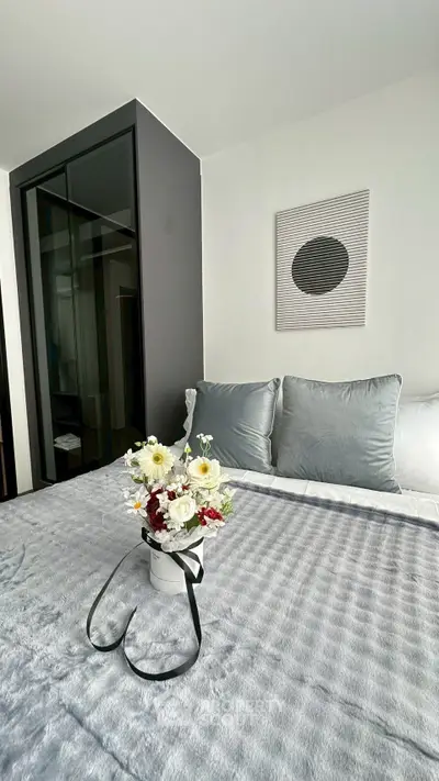 Modern bedroom with stylish decor and cozy bedding, featuring a floral arrangement for a touch of elegance.