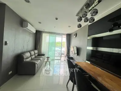 Modern living room with sleek furniture and large windows offering natural light and balcony access.