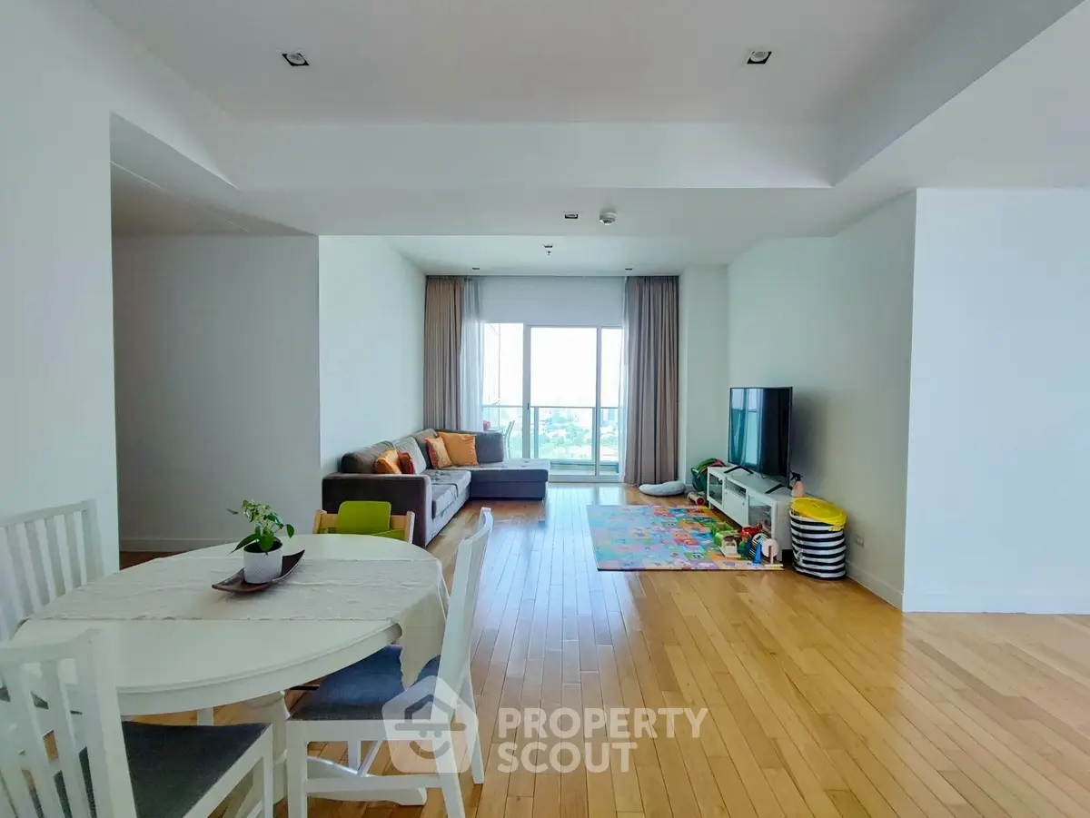 Spacious living room with hardwood floors and modern decor, featuring a cozy seating area and dining space.