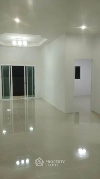 Spacious modern living room with glossy tiled floors and sliding glass doors.