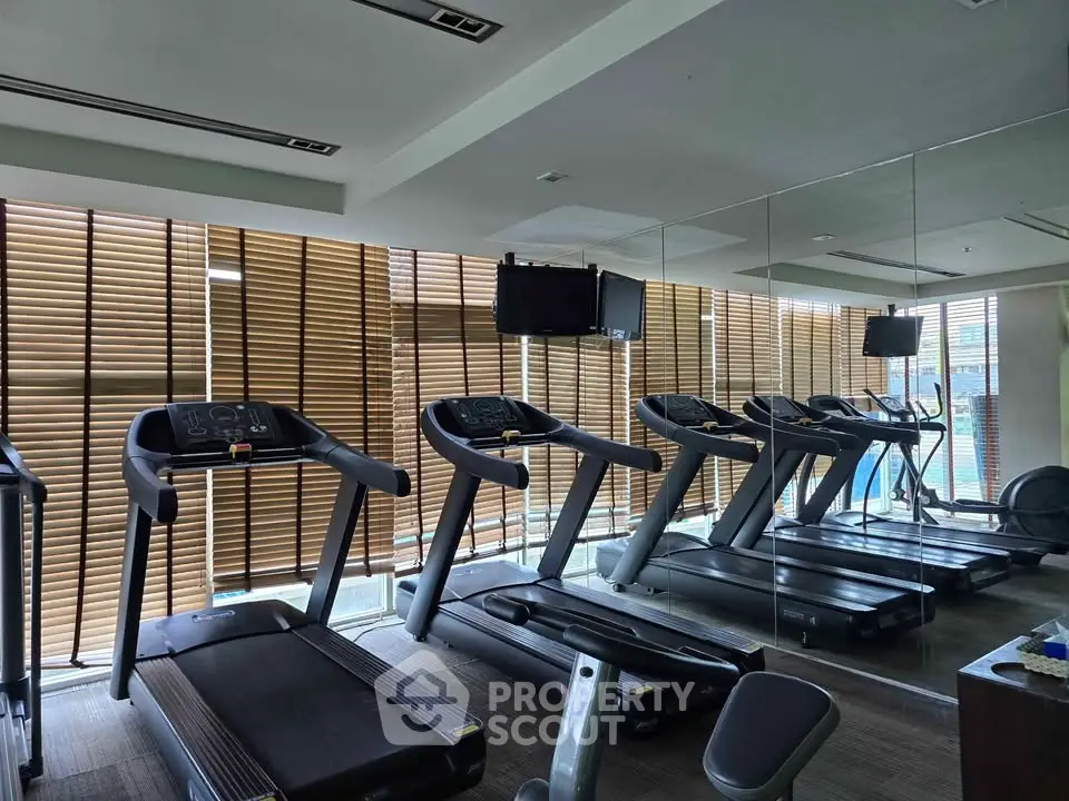 Modern gym with treadmills and mirrored walls in a luxury residential building.