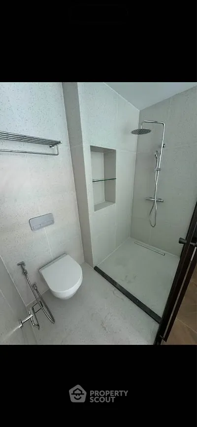 Modern bathroom with sleek shower and wall-mounted toilet in contemporary design.