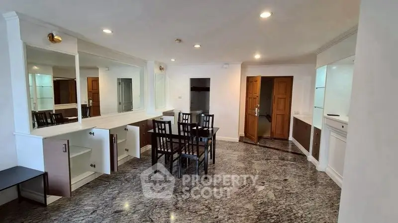 Spacious dining area with elegant marble flooring and modern furniture in a well-lit apartment.