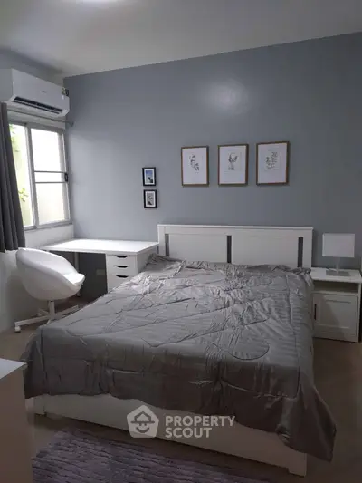 Modern bedroom with stylish decor and natural light, featuring a cozy bed and workspace.