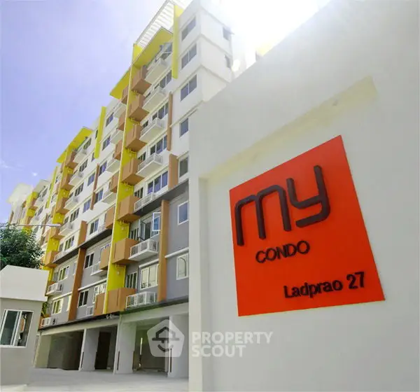 Modern condo building exterior with vibrant colors and signage at Ladprao 27.