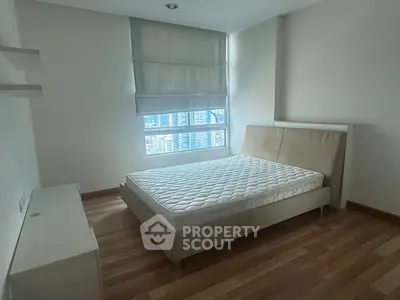 Spacious bedroom with large window and modern bed in high-rise apartment.