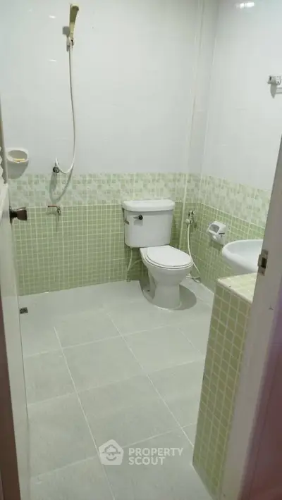 Modern bathroom with green tile accents and white fixtures.