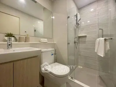 Modern bathroom with glass shower and sleek fixtures in contemporary home.