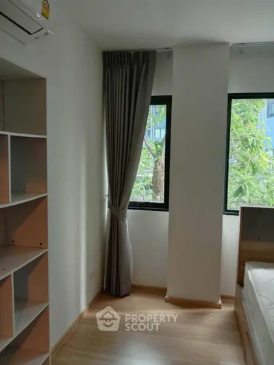 Bright bedroom with large windows and modern shelving unit, perfect for natural light lovers.