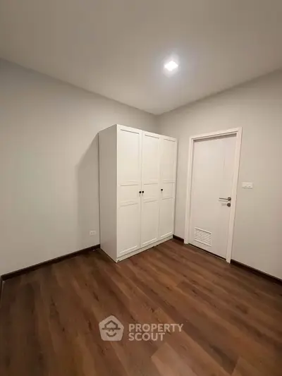 Minimalist bedroom with wooden flooring and white wardrobe