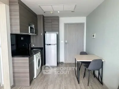 Modern compact kitchen with washing machine and dining area in sleek apartment.