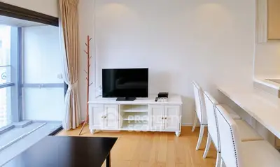 Modern living room with sleek TV stand and elegant bar stools, featuring a spacious balcony view.
