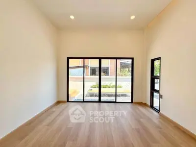 Spacious room with large windows and wooden flooring, offering ample natural light and a modern aesthetic.