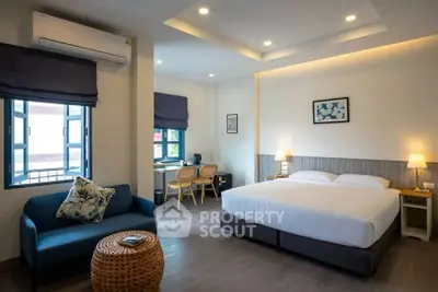 Spacious modern bedroom with cozy seating area and natural light