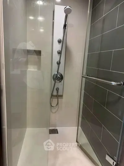 Modern shower with sleek glass door and rainfall showerhead in contemporary bathroom.