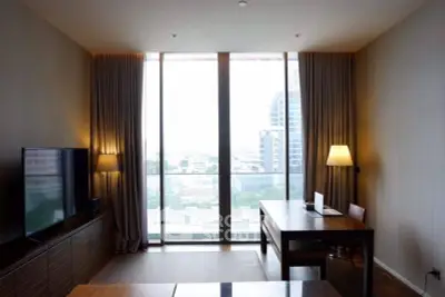 Spacious living room with floor-to-ceiling windows and city view, featuring modern furniture and ambient lighting.