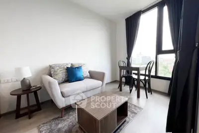 Modern living room with cozy sofa and dining area, featuring large windows and stylish decor.