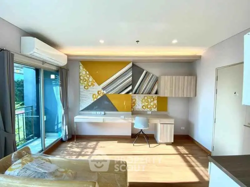Modern living room with stylish wall art and balcony access, featuring natural light and contemporary furniture.