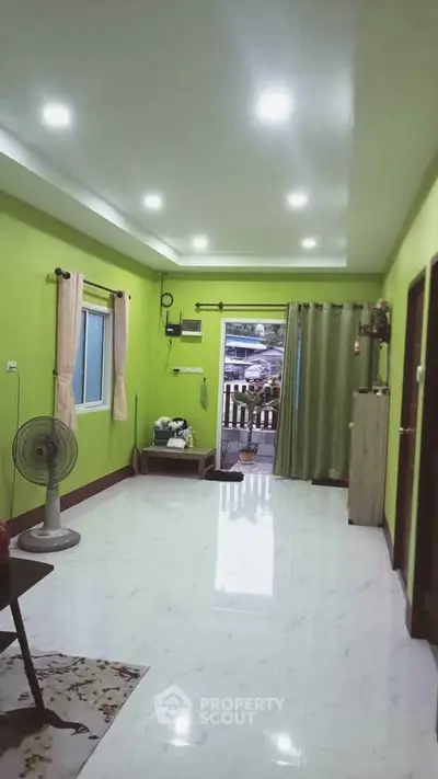 Spacious living room with green walls and white tiled floor, featuring modern lighting.