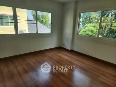 Spacious empty room with large windows and wooden flooring, ideal for customization.
