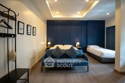 Spacious modern bedroom with stylish decor and cozy seating area.